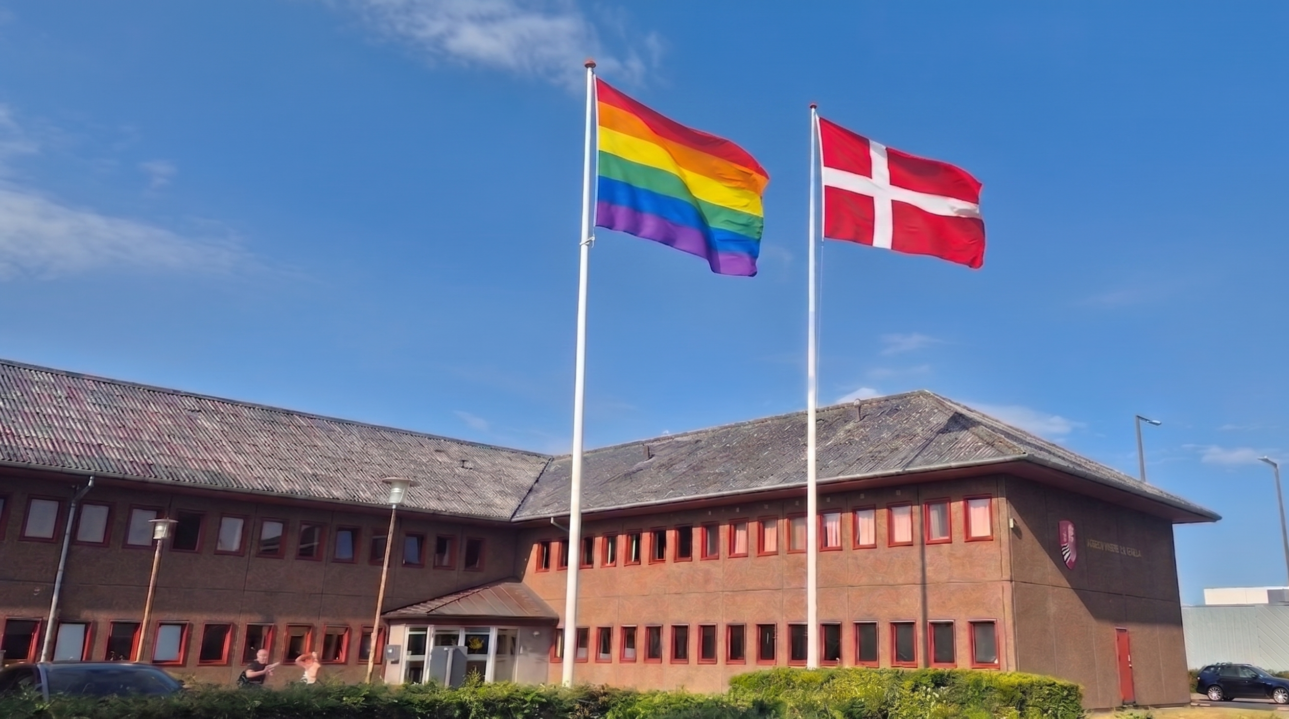 dannebrog og regnbueflag ved rådhuset. Foto: AI-manipuleret billede